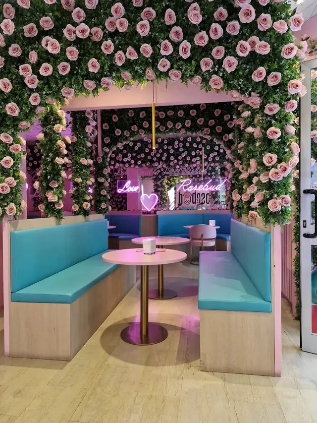 Sala con parete di rose e divani turchesi da Rosebud Biella